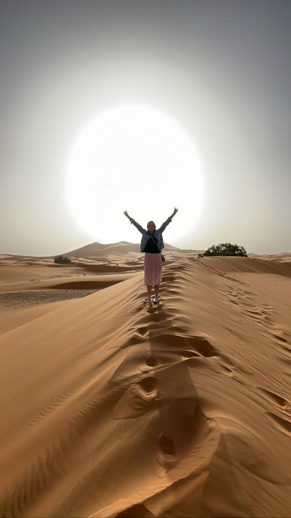 Agencia local  Marruecos  Turista levantando los brazos en las dunas del Sahara Marruecos.