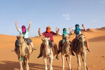 Grupo en camello posando con las manos en el aire en Marrakech